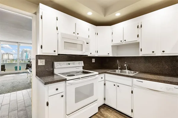 a kitchen with granite countertop white cabinets and white appliances