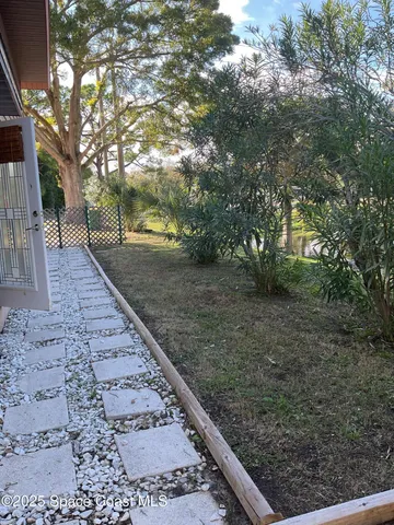 a view of a yard with plants and trees