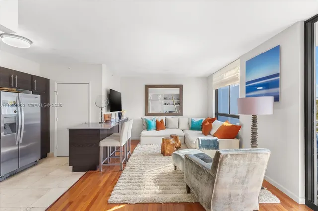 a living room with furniture a flat screen tv and a refrigerator