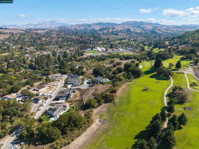an aerial view of a residential houses with outdoor space and trees