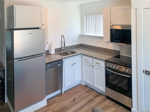 a kitchen with granite countertop white cabinets and refrigerator