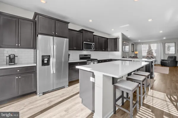 a kitchen with stainless steel appliances granite countertop a refrigerator a sink a stove a microwave and island