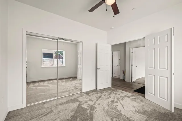 an empty room with windows and ceiling fan