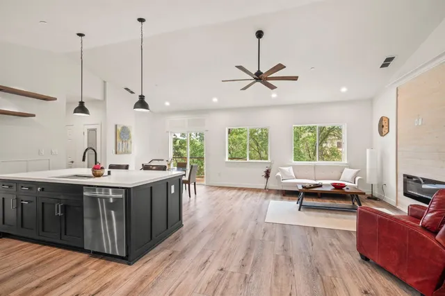 a view of living room with kitchen island stainless steel appliances a large window a couch and living room view