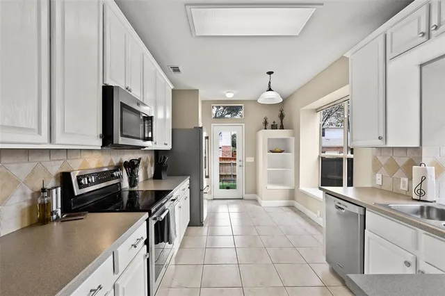 a kitchen with stainless steel appliances granite countertop a refrigerator a stove top oven a sink a dining table and chairs