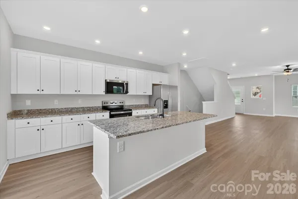 a large kitchen with stainless steel appliances granite countertop a sink a stove a microwave and a refrigerator