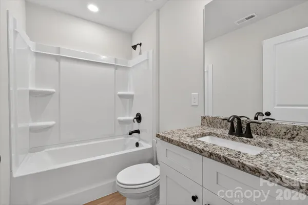 a bathroom with a granite countertop sink a toilet and shower
