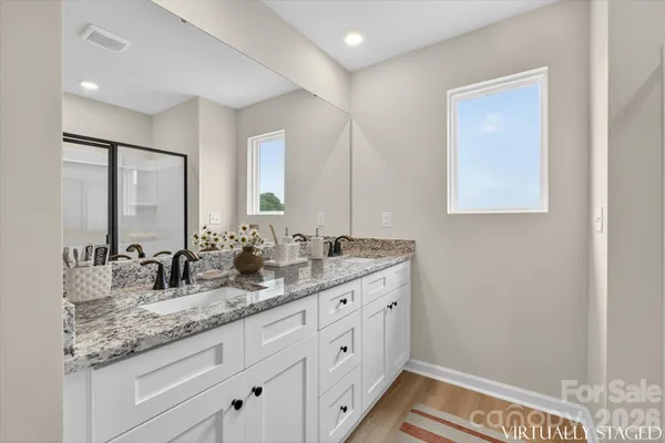 a bathroom with a granite countertop double vanity sink and mirror