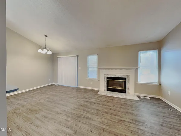an empty room with wooden floor fireplace and window