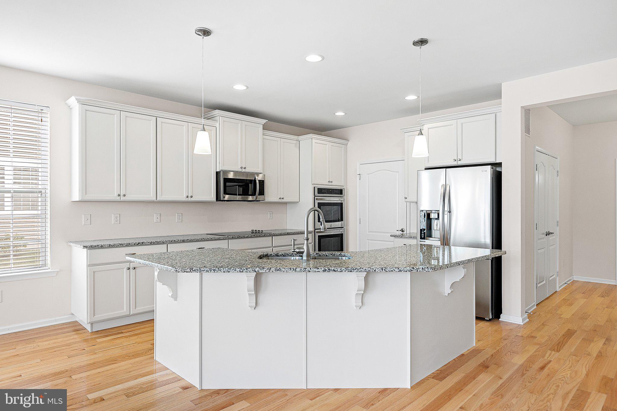 647 Vivaldi Drive Middletown, DE 19709 - Photo 6 of 38 a kitchen with stainless steel appliances granite countertop a stove a sink a refrigerator and white cabinets with wooden floor