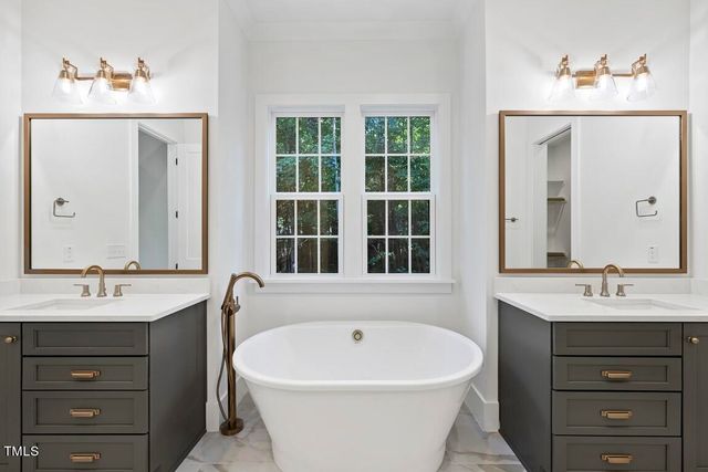 a bathroom with a bathtub a sink a window and a mirror