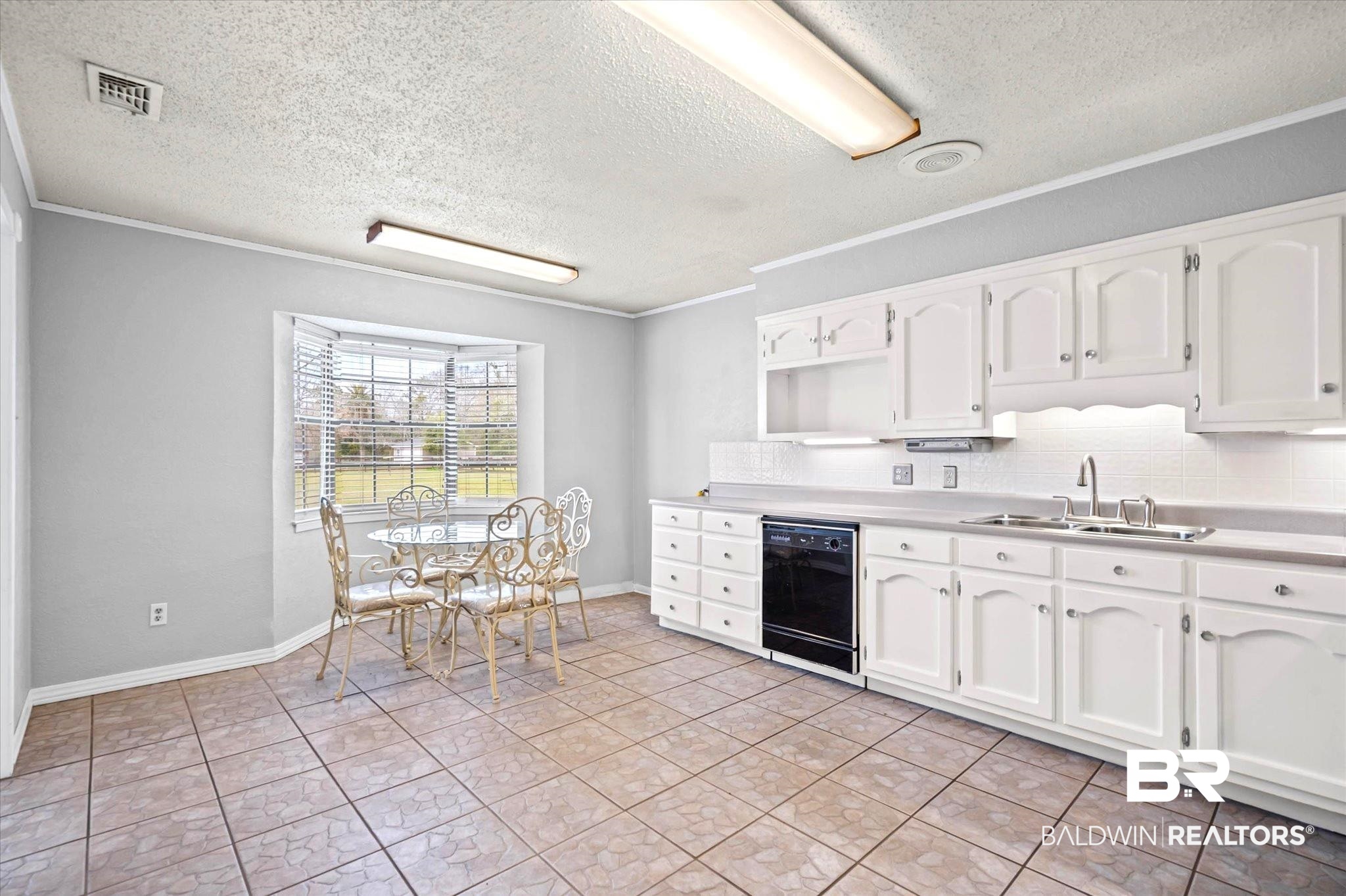 8090 Murray Hill Road Irvington, AL 36544 - Photo 14 of 40 Kitchen featuring white cabinetry, light countertops, black dishwasher, a textured ceiling, and backsplash
