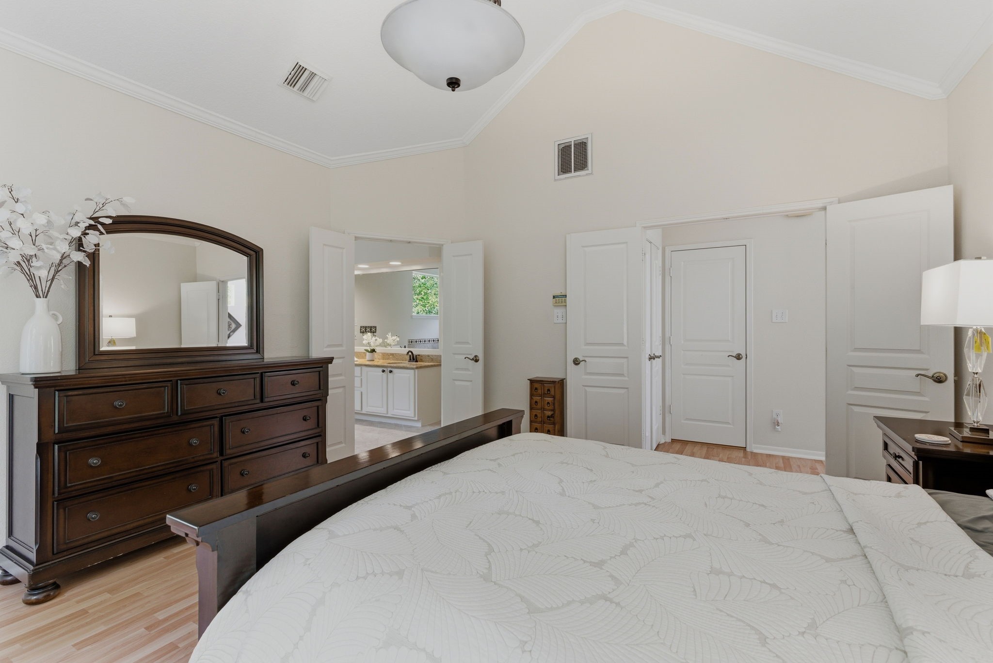 11 Dovewing Place Spring, TX 77382 - Photo 20 of 32 This bedroom features a vaulted ceiling and neutral walls, creating an airy feel and access to an en-suite bathroom. The space is bright and inviting, with ample natural light.