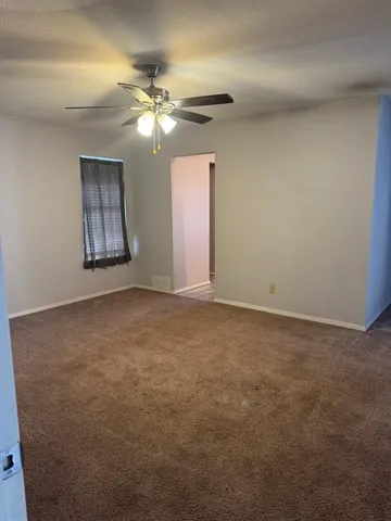 a view of an empty room with window and chandelier fan
