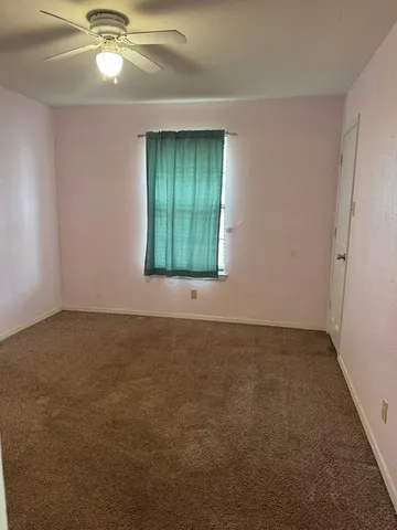 an empty room with a chandelier fan and windows