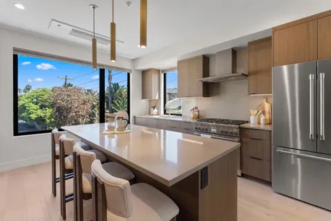 a kitchen with stainless steel appliances granite countertop a table chairs refrigerator and sink