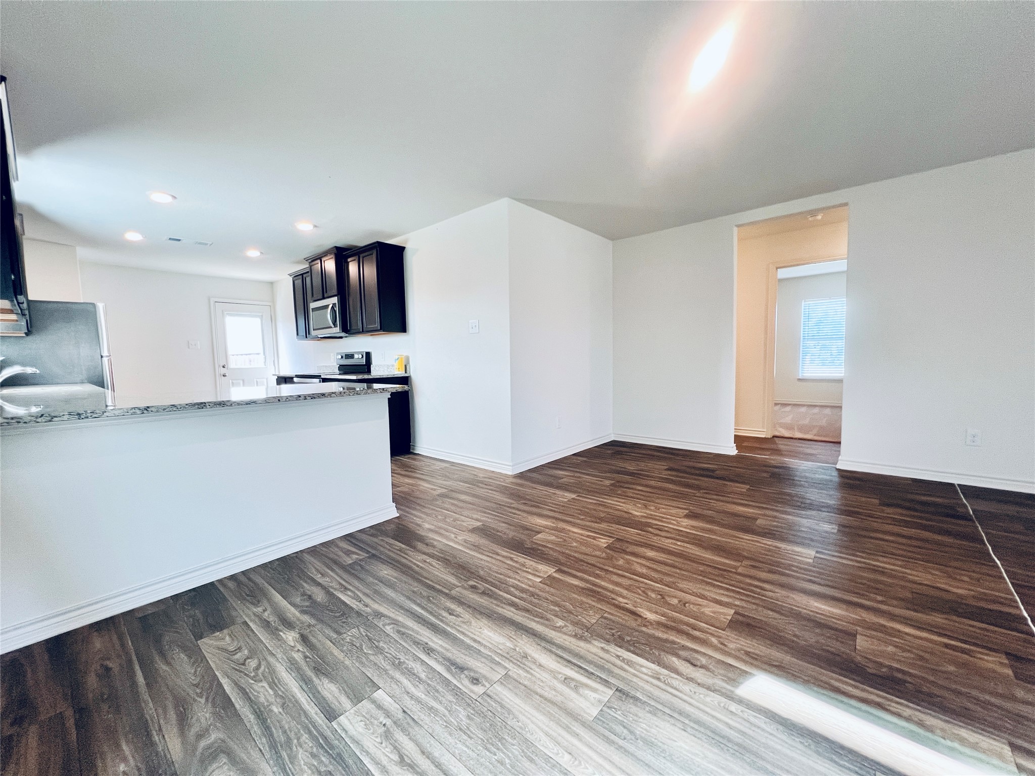 520 Locksley Cove Jarrell, TX 76537 - Photo 26 of 27 An open floorplan seamlessly connects the well-appointed kitchen with rich cabinetry and durable wood-look flooring throughout.