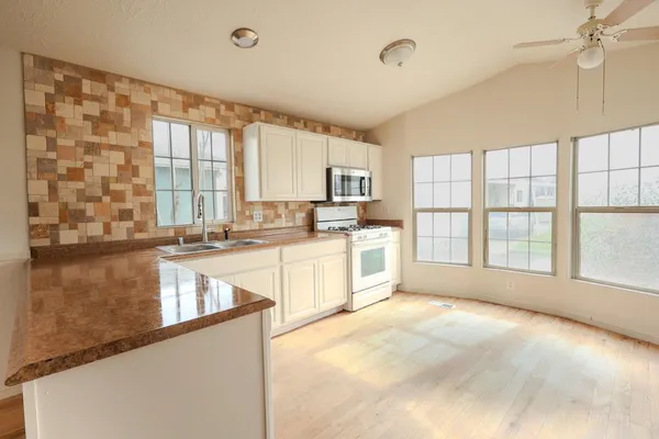 a large kitchen with kitchen island a large window appliances and cabinets