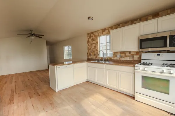 a kitchen with granite countertop a sink cabinets stainless steel appliances and a window