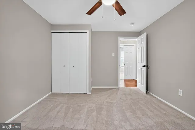 an empty room with ceiling fan and window