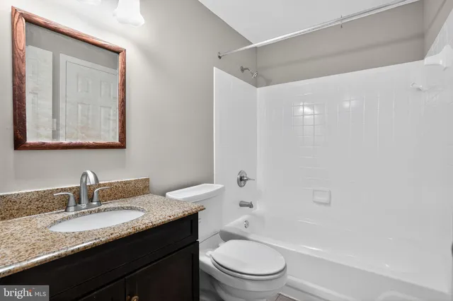 a bathroom with a granite countertop sink a toilet and shower
