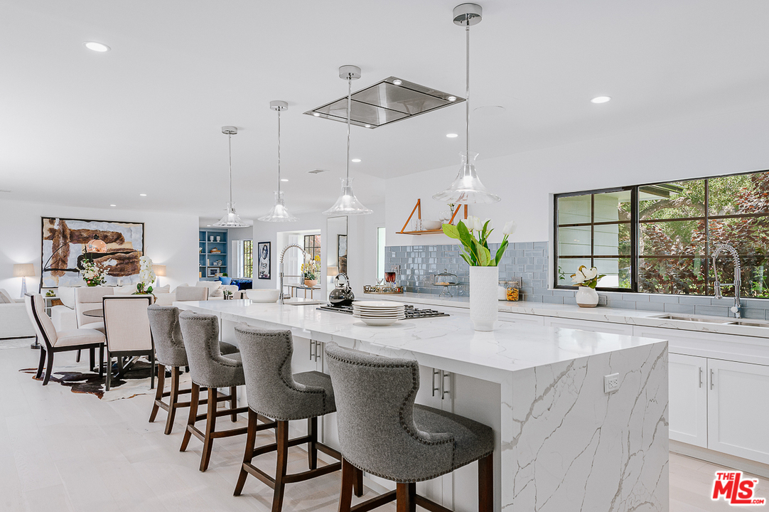 1075 Moraga Drive Los Angeles, CA 90049 - Photo 3 of 24 a kitchen with a dining table chairs and white cabinets