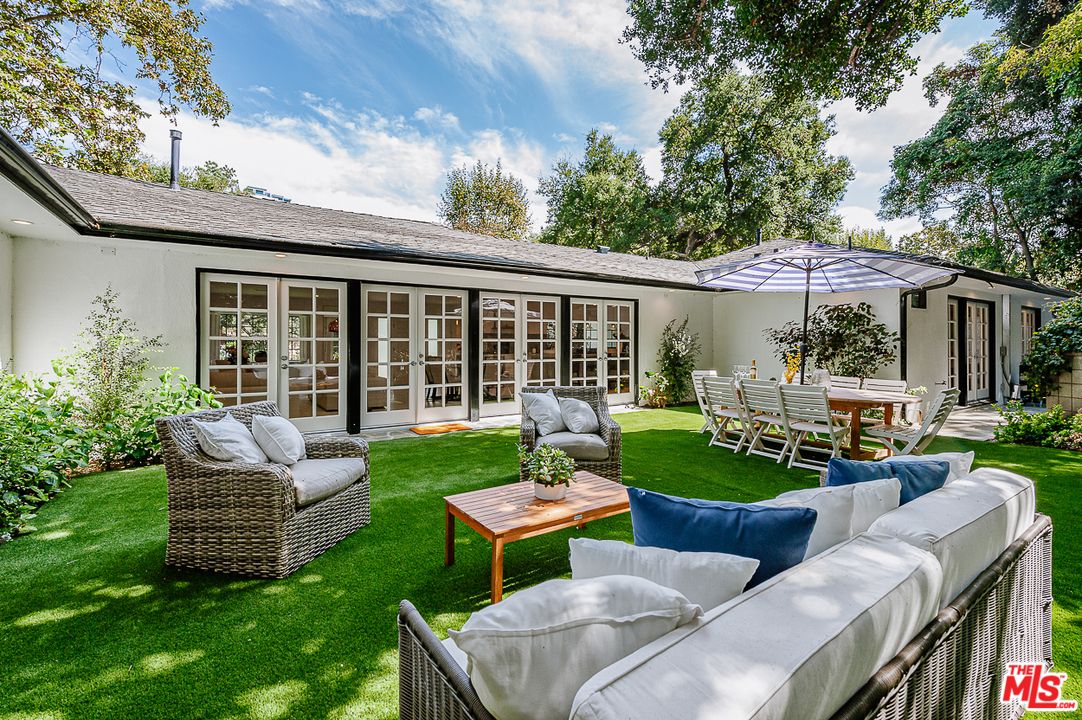 1075 Moraga Drive Los Angeles, CA 90049 - Photo 22 of 24 a view of a patio with couches chairs and a yard