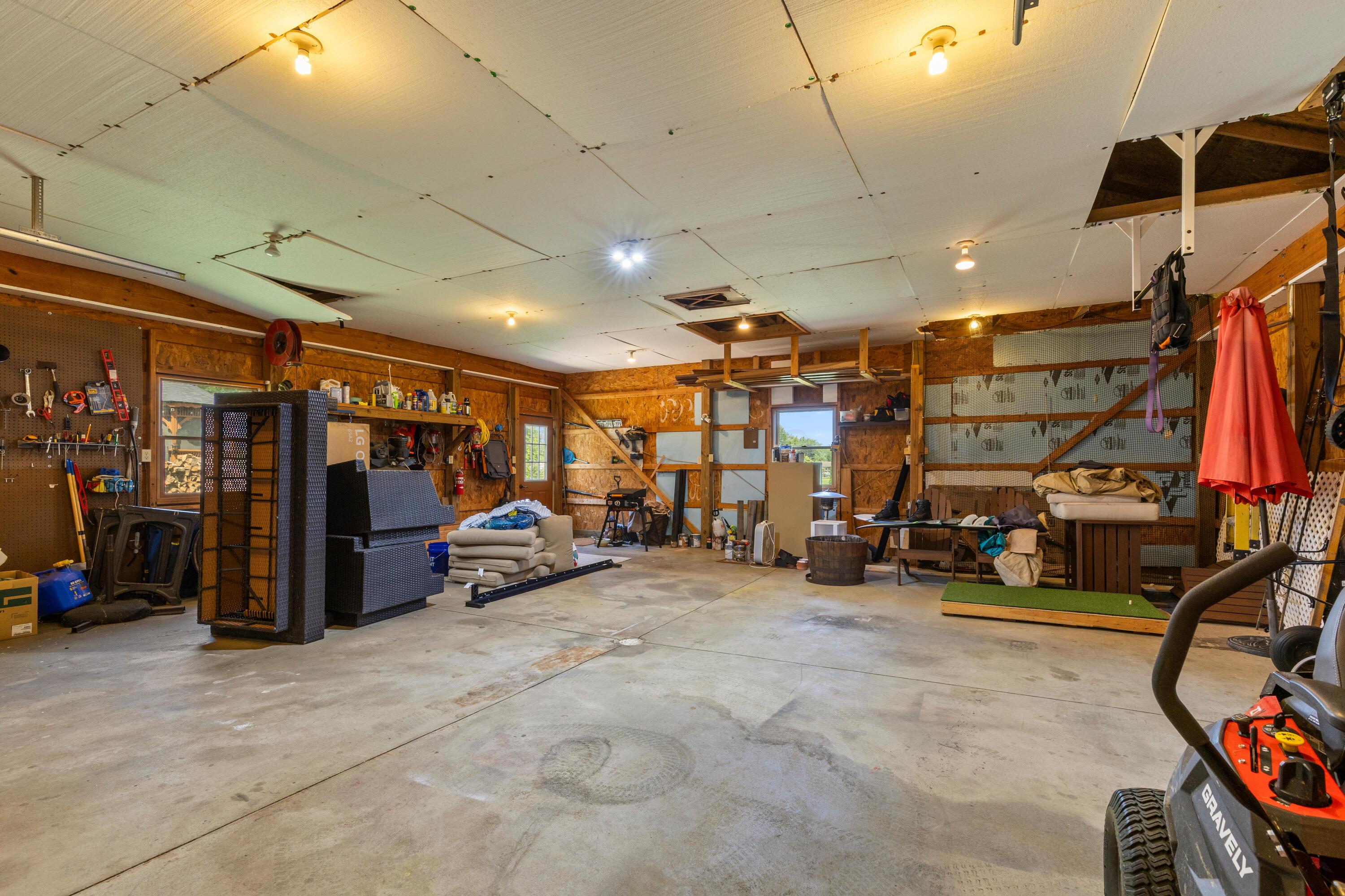 1515 Dale Ford Road Delaware, OH 43015 - Photo 59 of 74 • Vinyl exterior • 4 car tandem • Concrete flooring • Ceiling lights • Electric panel (tied to the house) • Dog door • Pegboard walls • Shelves • Golf net remains