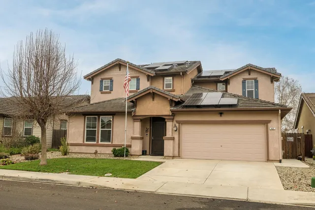 a front view of a house with a garden and trees