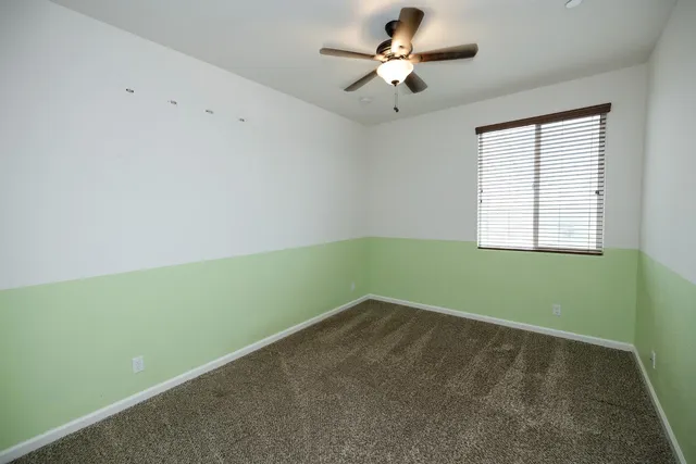 an empty room with windows and chandelier fan