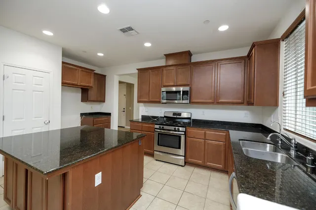a kitchen with stainless steel appliances granite countertop a sink a stove and cabinets