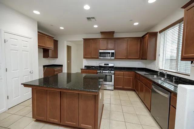 a kitchen with stainless steel appliances granite countertop a stove a sink and a microwave