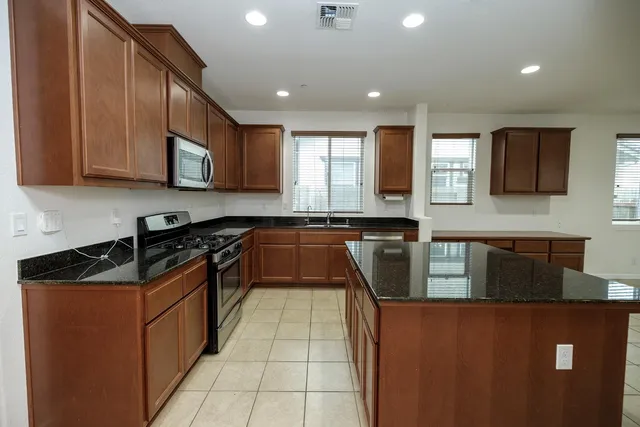 a kitchen with kitchen island granite countertop a sink a counter top space appliances and cabinets