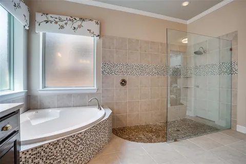 a bathroom with a tub a window and a glass door shower