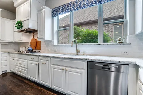 a kitchen with granite countertop stainless steel appliances a sink window and cabinets