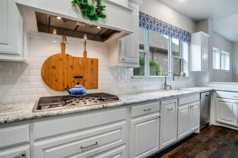 a kitchen with stainless steel appliances granite countertop a sink a stove and cabinets