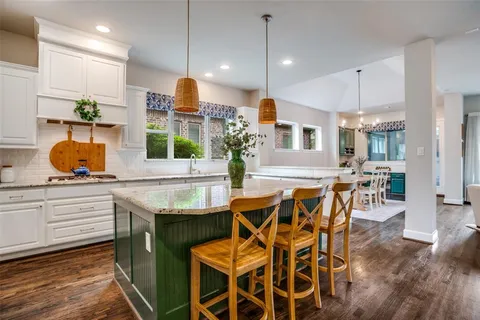 a kitchen with stainless steel appliances granite countertop a table and chairs in it