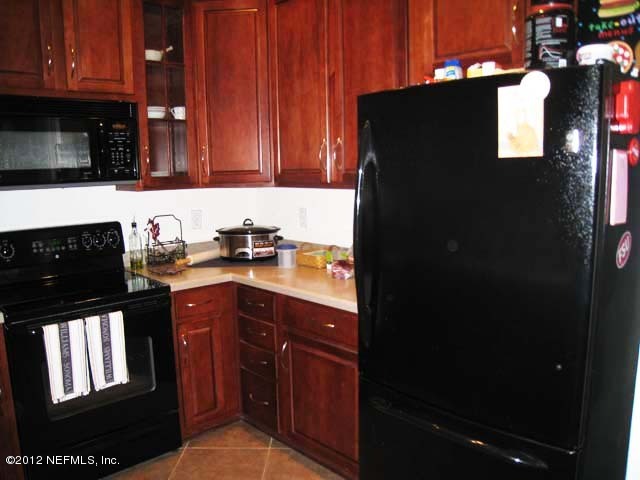 12993 Spring Rain Road Jacksonville, FL 32258 - Photo 5 of 24 a kitchen with granite countertop white cabinets and black appliances