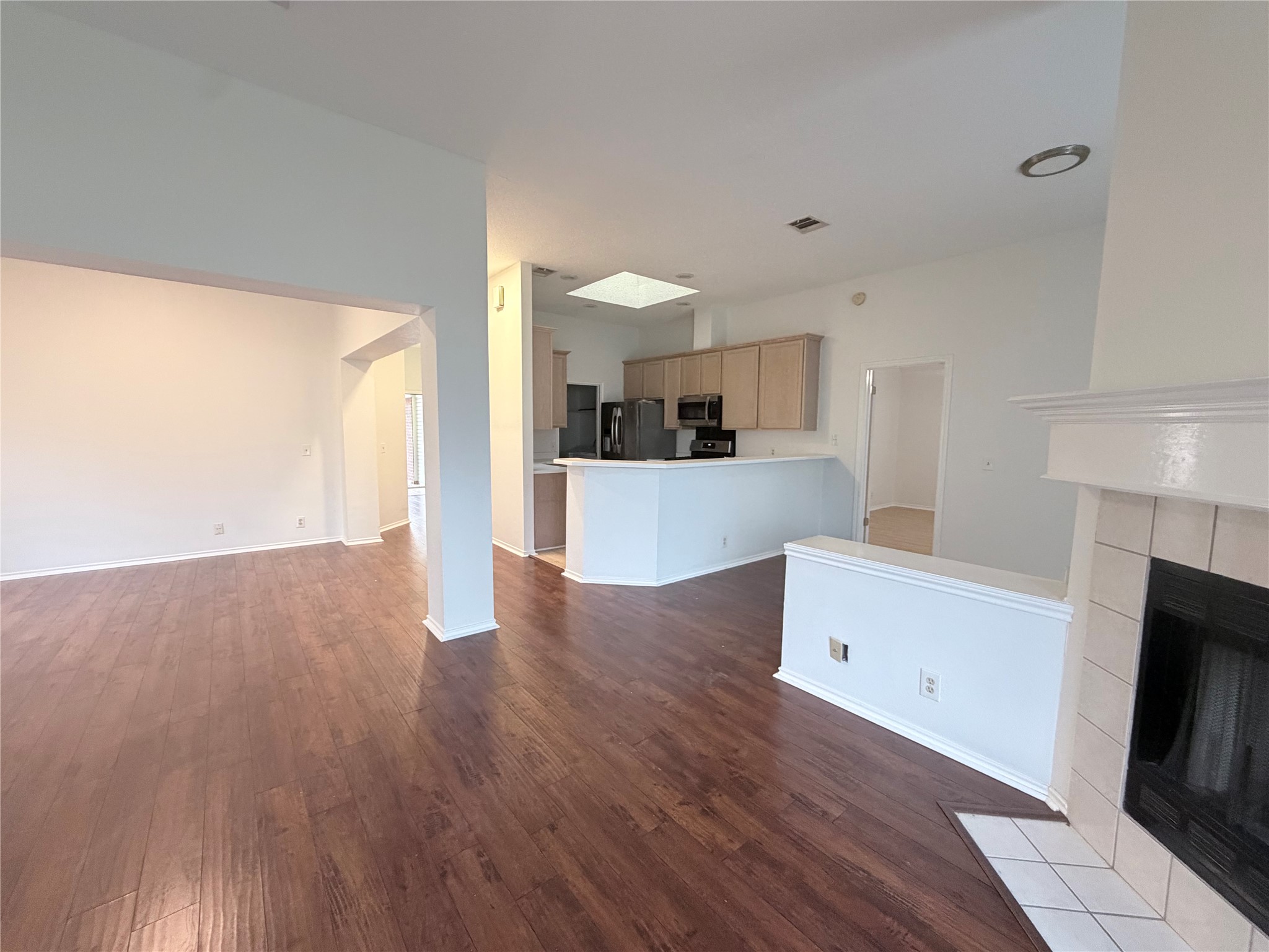 20809 Pacers Gait Lane Pflugerville, TX 78660 - Photo 11 of 23 Unfurnished living room with a tiled fireplace and dark wood-style flooring