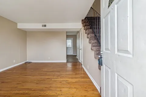 a view of a hallway to an empty room with wooden floor and entryway