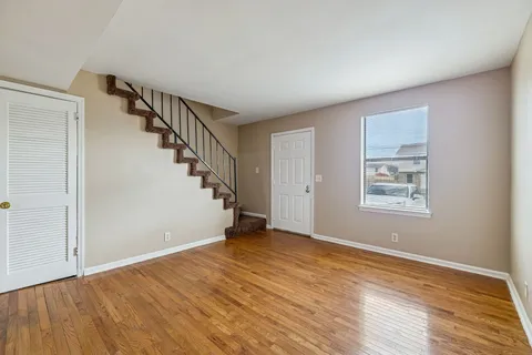 a view of an empty room with wooden floor and stairs