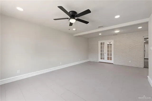 an empty room with ceiling fan and windows