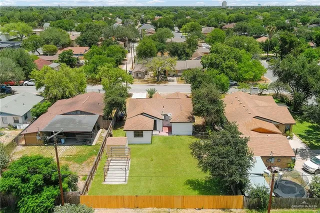 an aerial view of a house with swimming pool and large trees