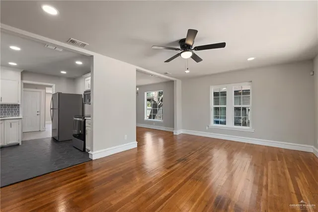 a view of an empty room with wooden floor and a window