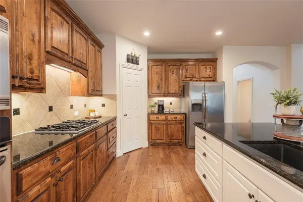 a kitchen with granite countertop a sink stove refrigerator and cabinets