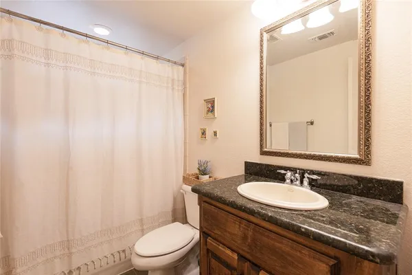 a bathroom with a granite countertop sink toilet a mirror and a shower