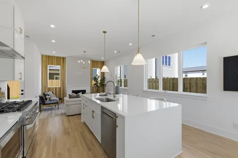 a kitchen with stainless steel appliances kitchen island granite countertop a stove a sink a dining table and chairs with wooden floor