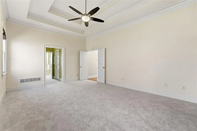 an empty room with chandelier fan and windows