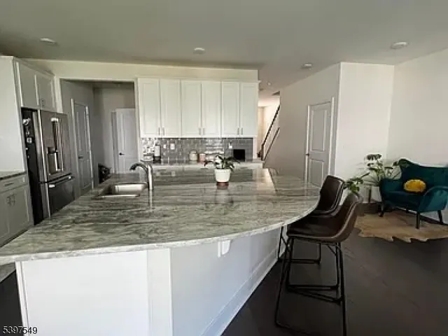 a view of a kitchen with kitchen island dining table a sink and a refrigerator