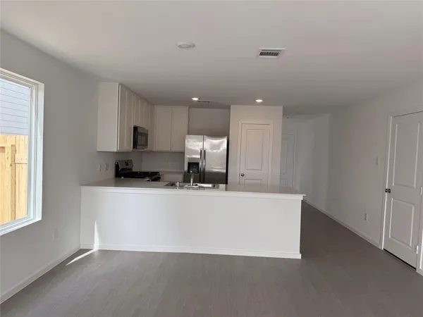 a living room with stainless steel appliances a refrigerator a sink dishwasher with a dining table and chairs